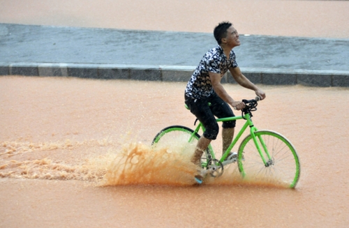 5月11日，一名行人在深圳街頭冒雨騎行。